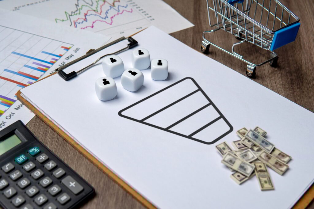 A clipboard with a sales funnel diagram and dice representing customers.
