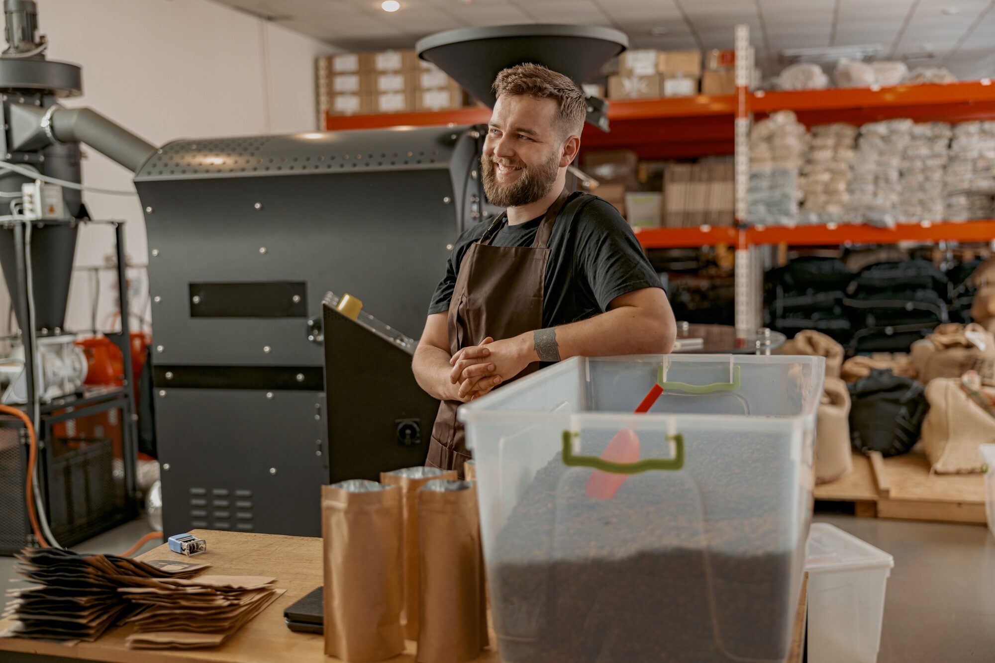 Portrait of smiling business owner on background of own small coffee factory looking away
